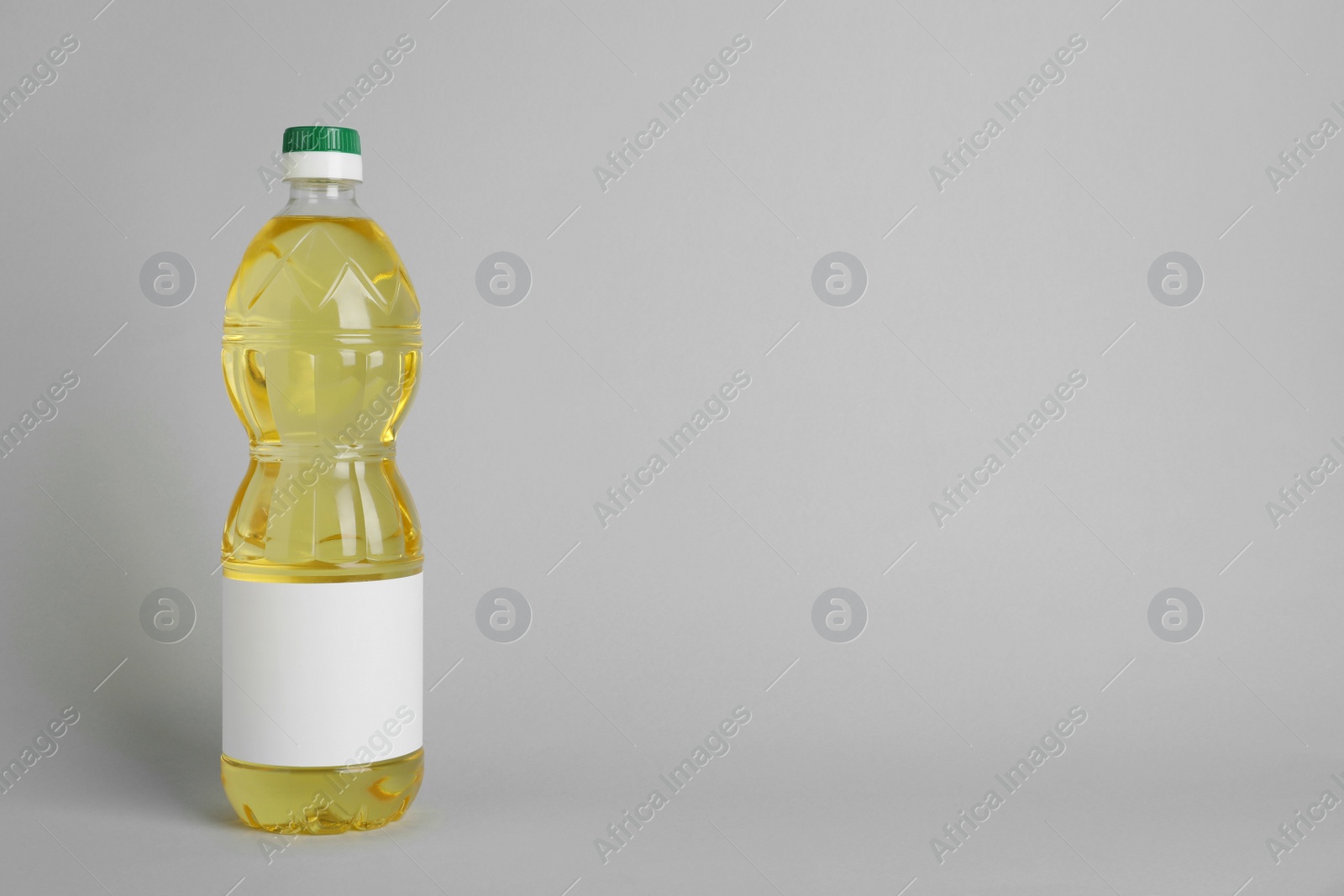 Photo of Bottle of cooking oil on light grey background. Space for text