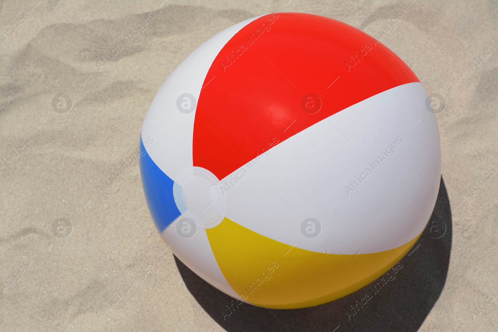 Photo of Colorful beach ball on sand, above view