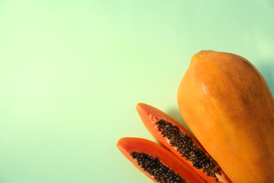 Photo of Fresh ripe cut and whole papaya fruits on light green background, flat lay. Space for text