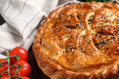 Photo of Tasty homemade pie and fresh tomatoes on grey table