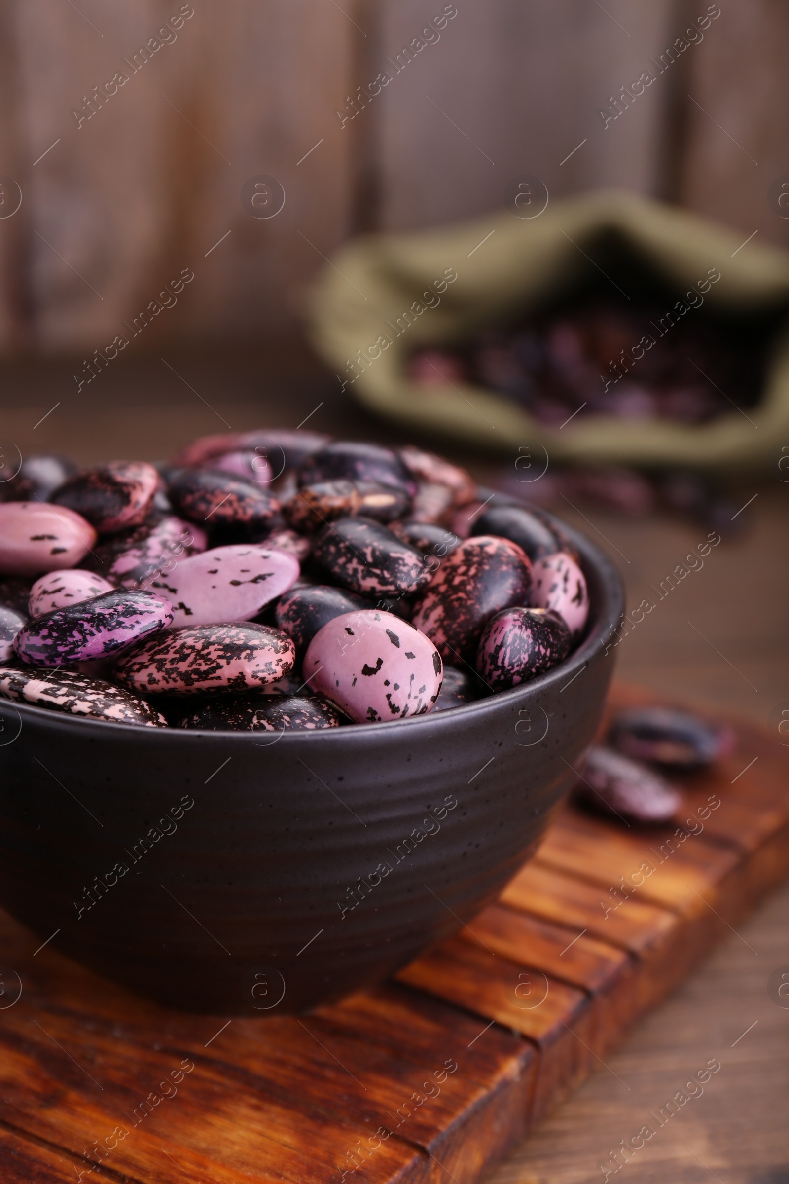 Photo of Bowl with dry kidney beans on wooden table, closeup