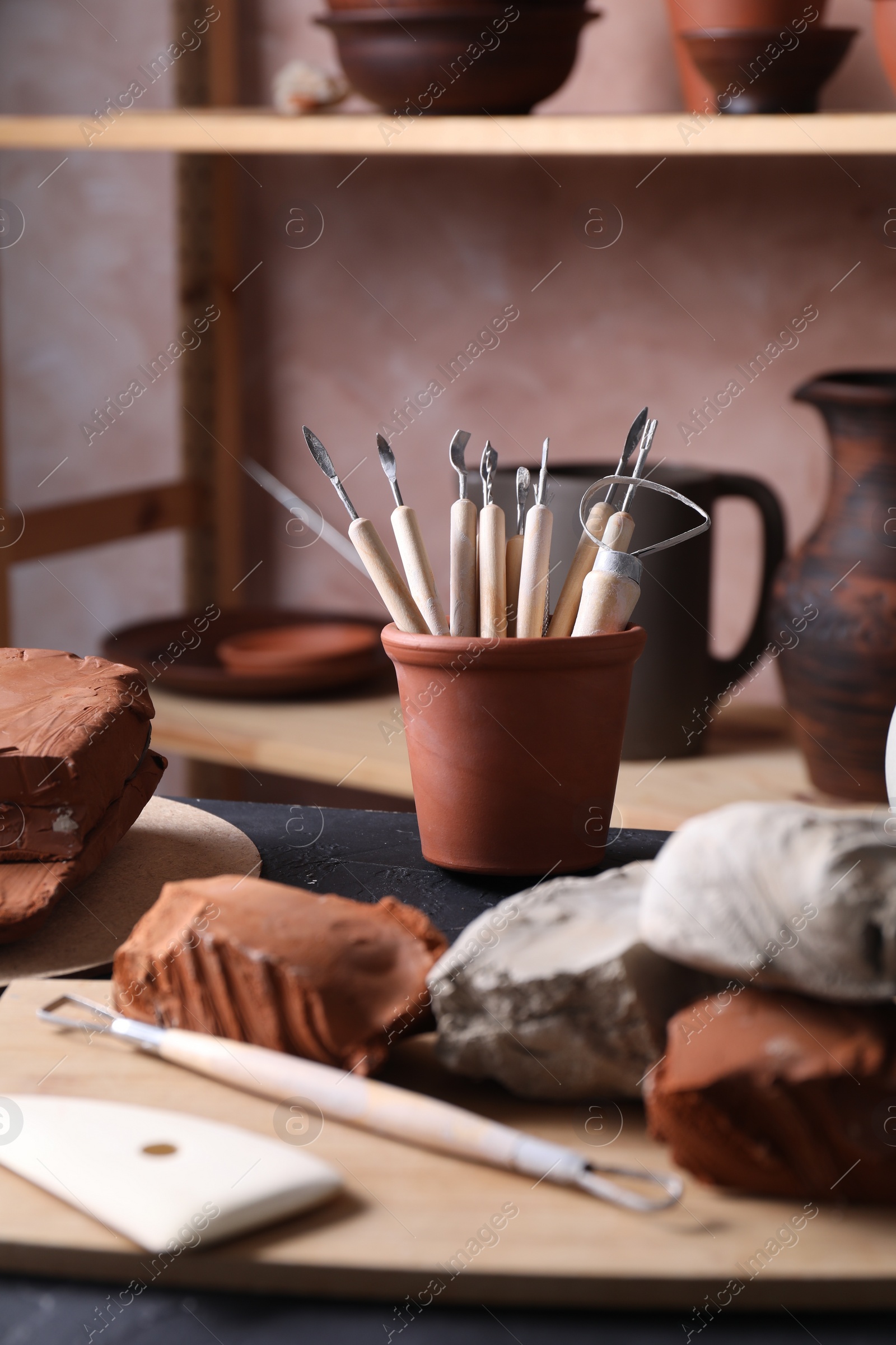 Photo of Clay and set of modeling tools on table in workshop