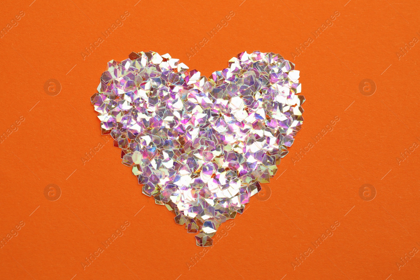 Photo of Heart made with shiny glitter on orange background, flat lay