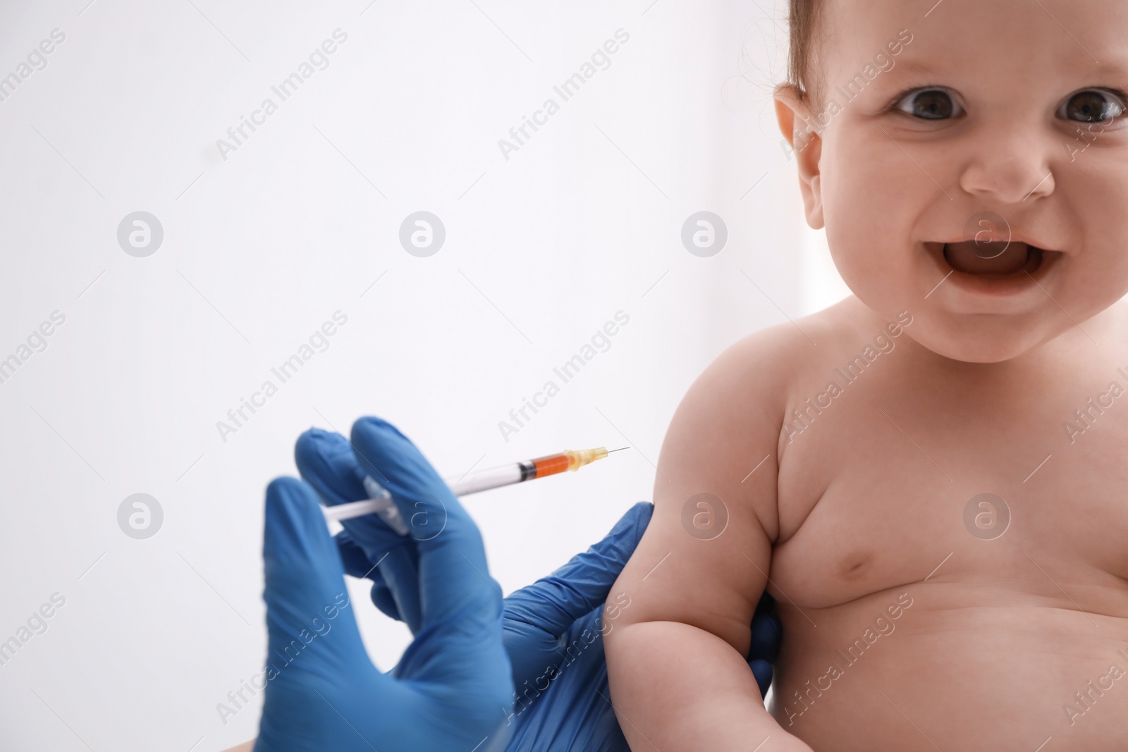Photo of Doctor vaccinating baby against light background. Health care