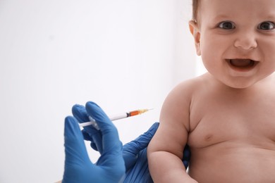 Doctor vaccinating baby against light background. Health care