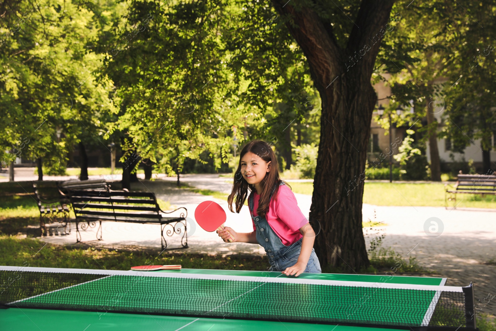 Photo of Little girl playing ping pong in park