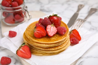 Photo of Tasty pancakes with fresh berries and honey on white marble table