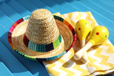 Mexican sombrero hat, towel and maracas on blue wooden surface