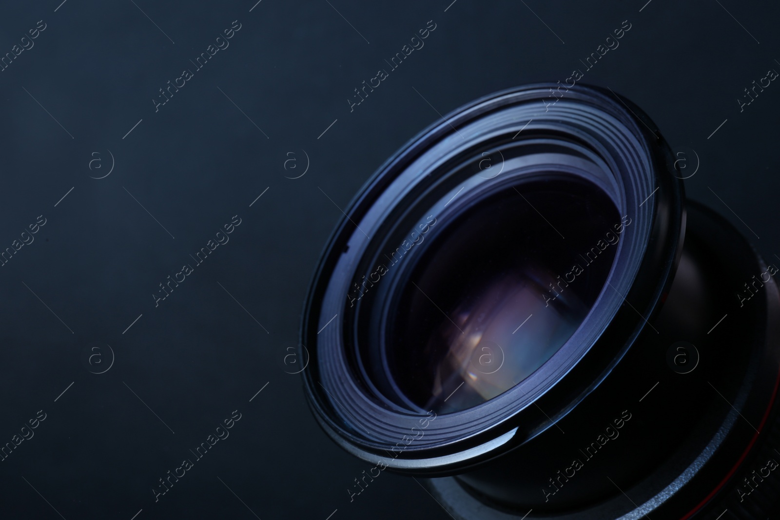 Photo of Lens of professional camera on dark blue background, closeup. Space for text