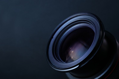 Lens of professional camera on dark blue background, closeup. Space for text