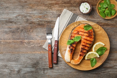 Plate with tasty salmon steak on wooden background