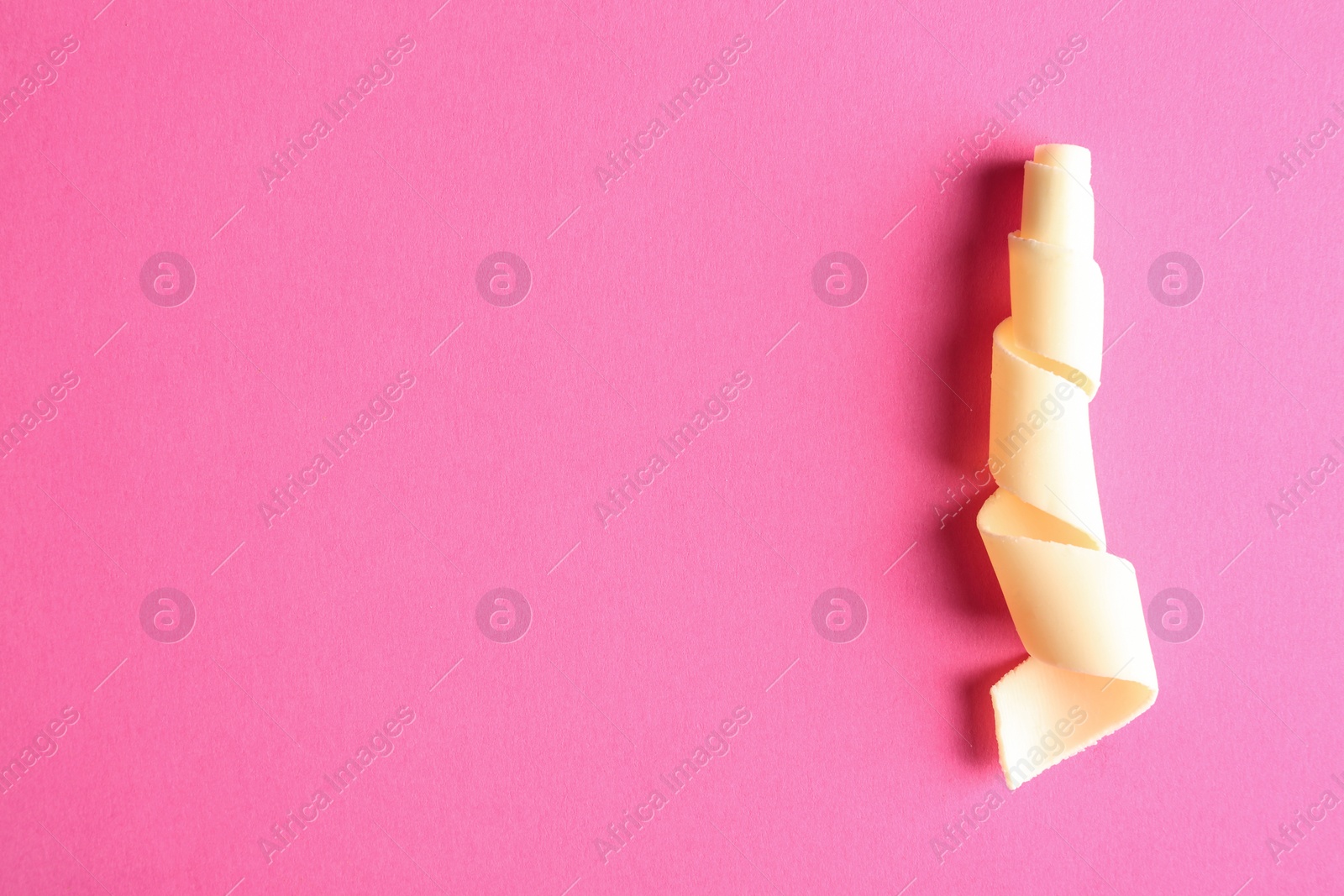 Photo of Yummy white chocolate curl and space for text on color background, top view