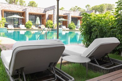 Photo of Sunbeds near outdoor swimming pool at luxury resort