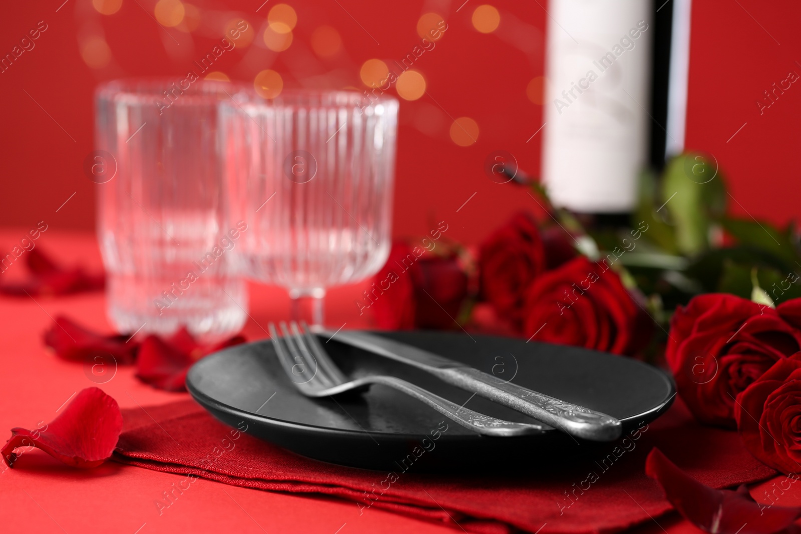 Photo of Place setting with roses on red table, closeup. Romantic dinner