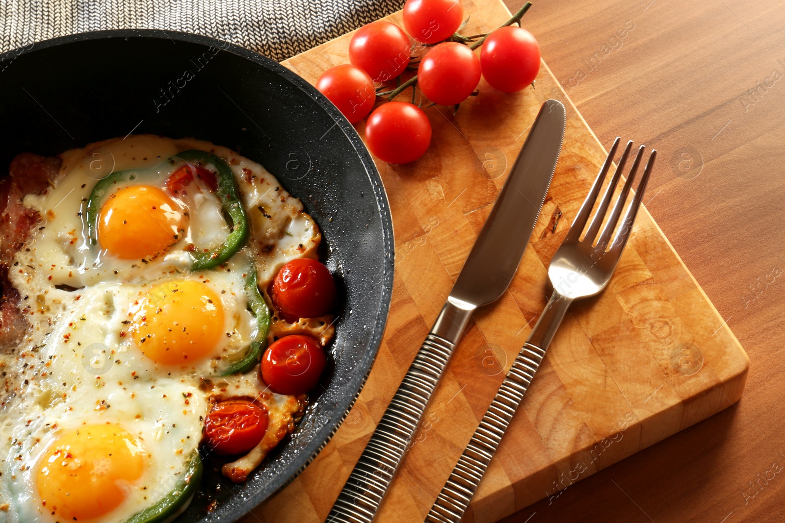 Photo of Delicious fried eggs with bacon, tomatoes and pepper served on wooden table