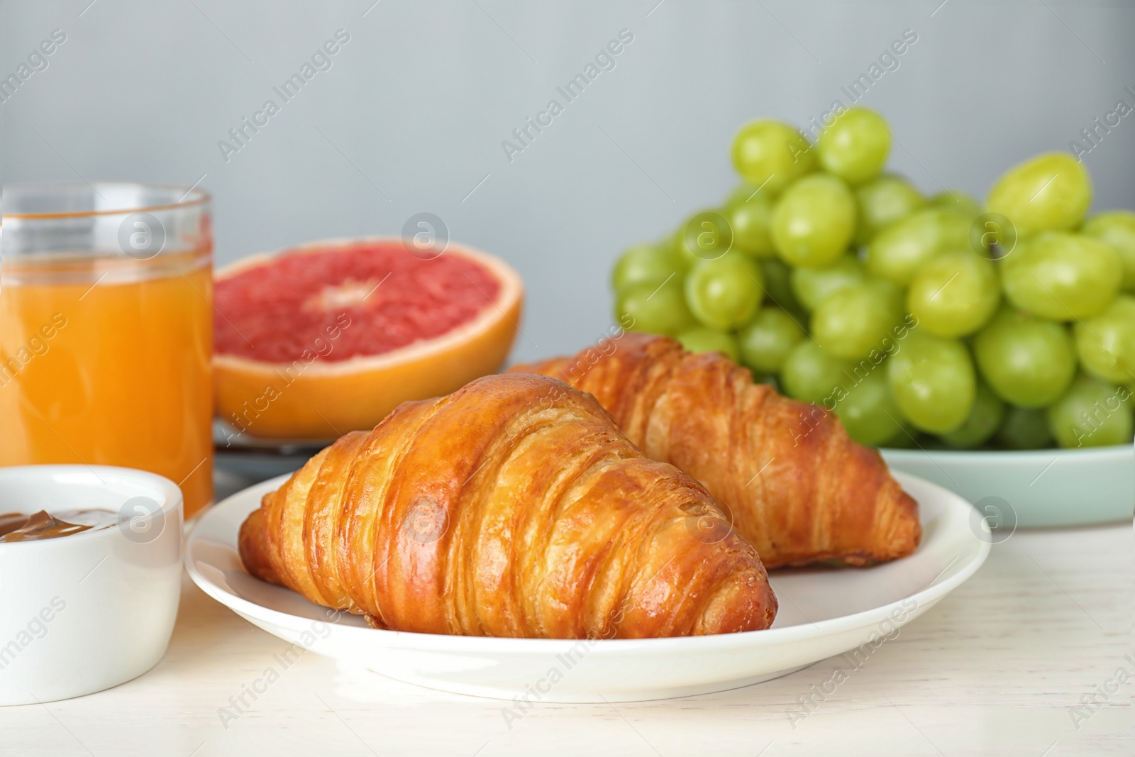 Photo of Delicious breakfast with croissants served on white wooden table