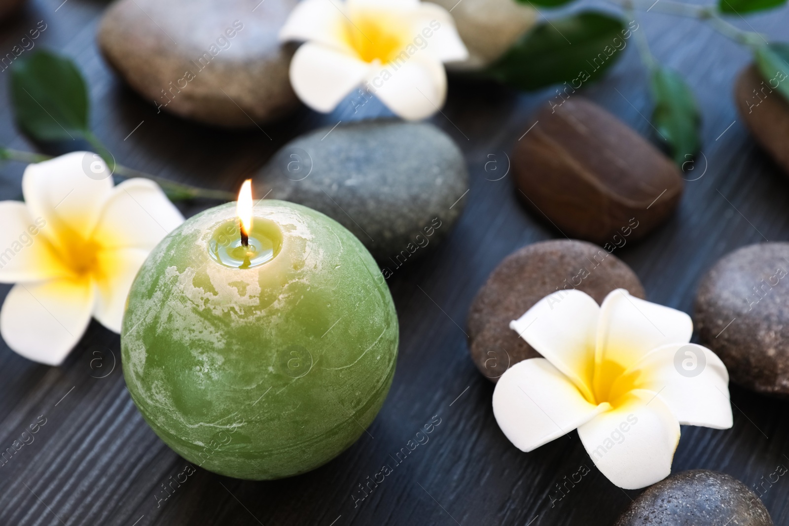 Photo of Composition with spa stones, flowers and candle on wooden background