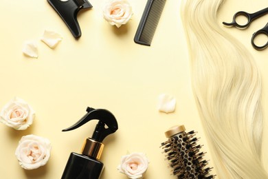 Photo of Flat lay composition with different hairdresser tools and flowers on pale yellow background, space for text