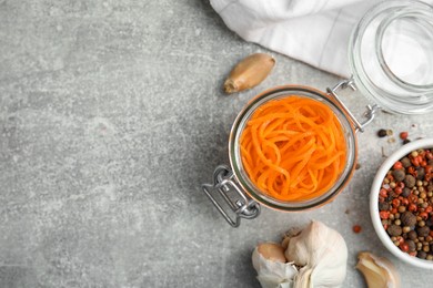 Photo of Delicious Korean carrot salad, garlic and spices on grey table, flat lay. Space for text