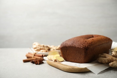 Photo of Delicious gingerbread cake and ingredients on light grey table, space for text