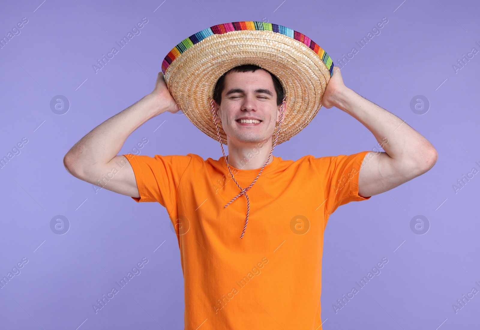 Photo of Young man in Mexican sombrero hat on violet background