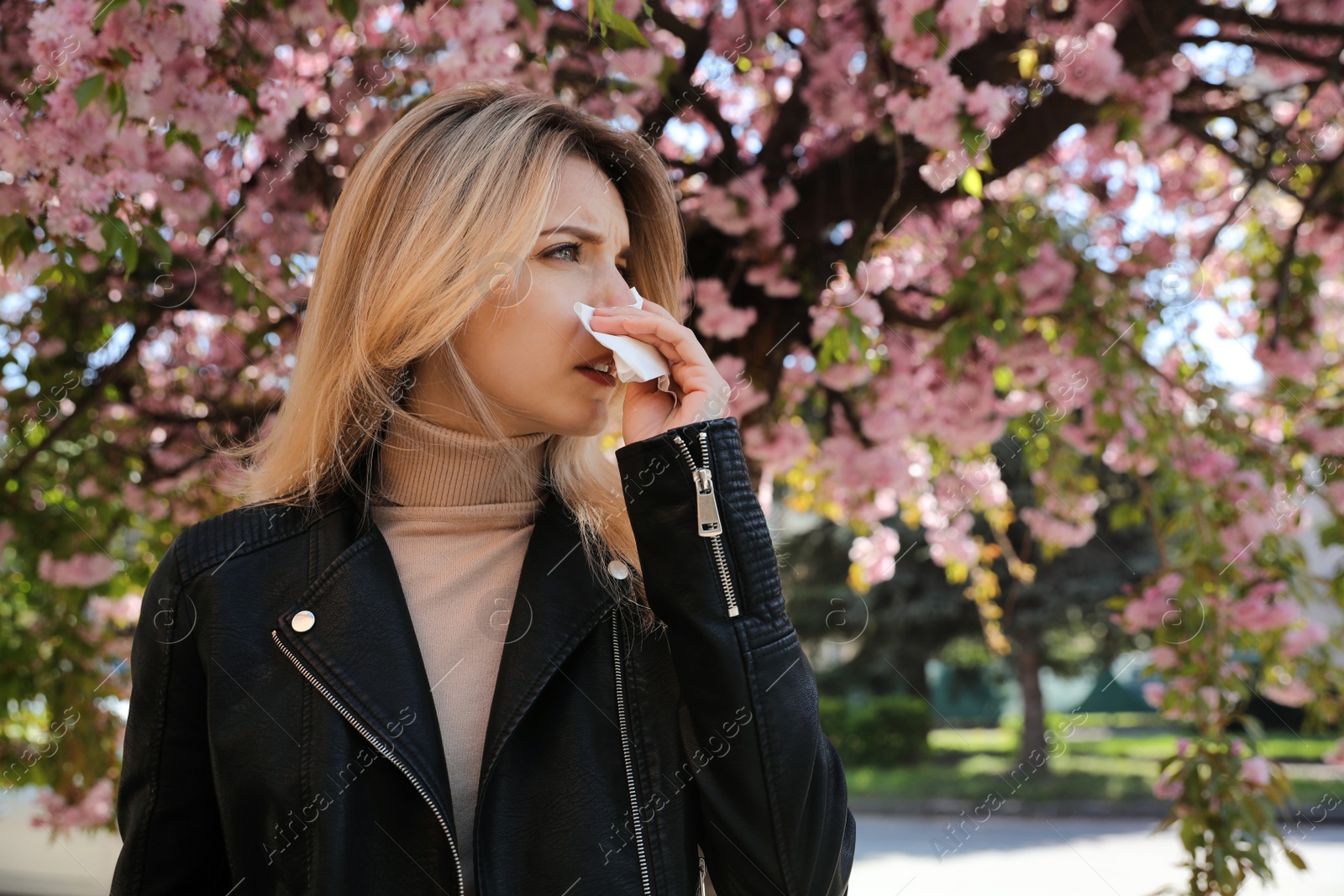 Photo of Woman suffering from seasonal pollen allergy near blossoming tree outdoors