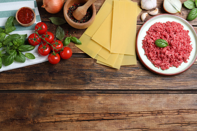 Fresh lasagna ingredients on wooden table, flat lay. Space for text