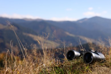 Photo of Binoculars on grass in mountains, space for text