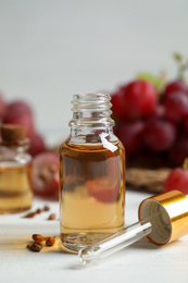 Photo of Bottle of natural grape seed oil on white wooden table. Organic cosmetic
