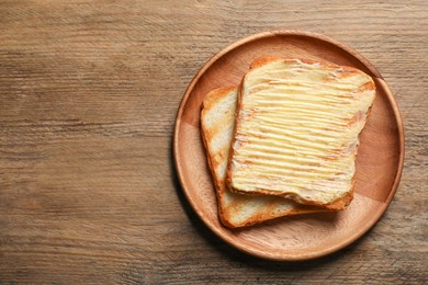 Photo of Tasty toasts with butter on wooden table, top view. Space for text
