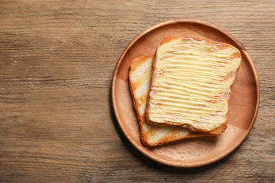 Tasty toasts with butter on wooden table, top view. Space for text