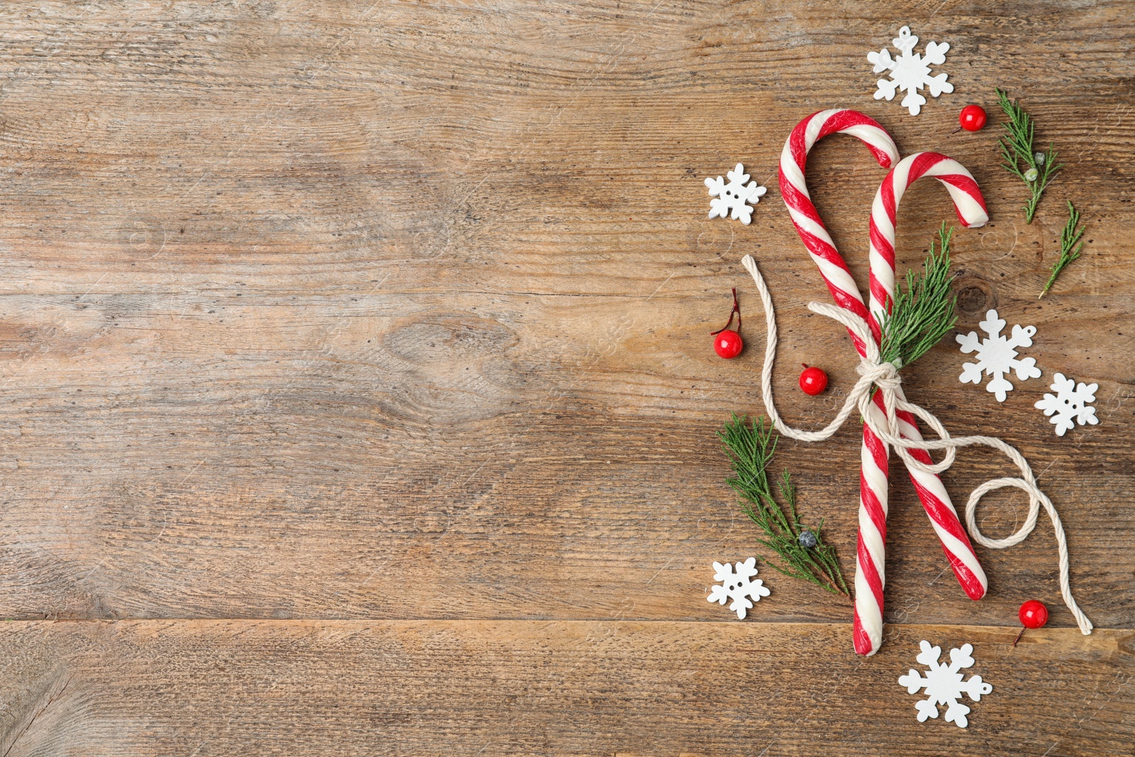 Photo of Flat lay composition with candy canes on wooden background, space for text. Winter holidays