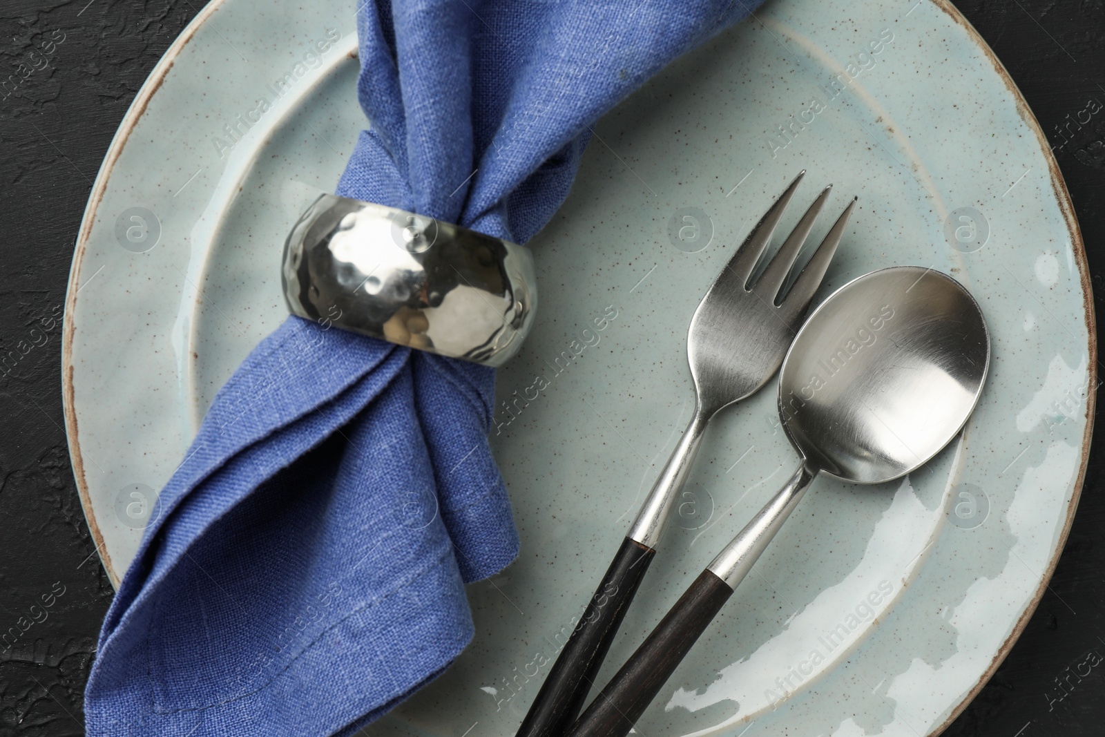 Photo of Stylish setting with cutlery, napkin and plate on dark table, top view