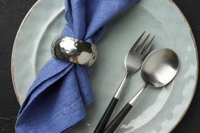 Stylish setting with cutlery, napkin and plate on dark table, top view