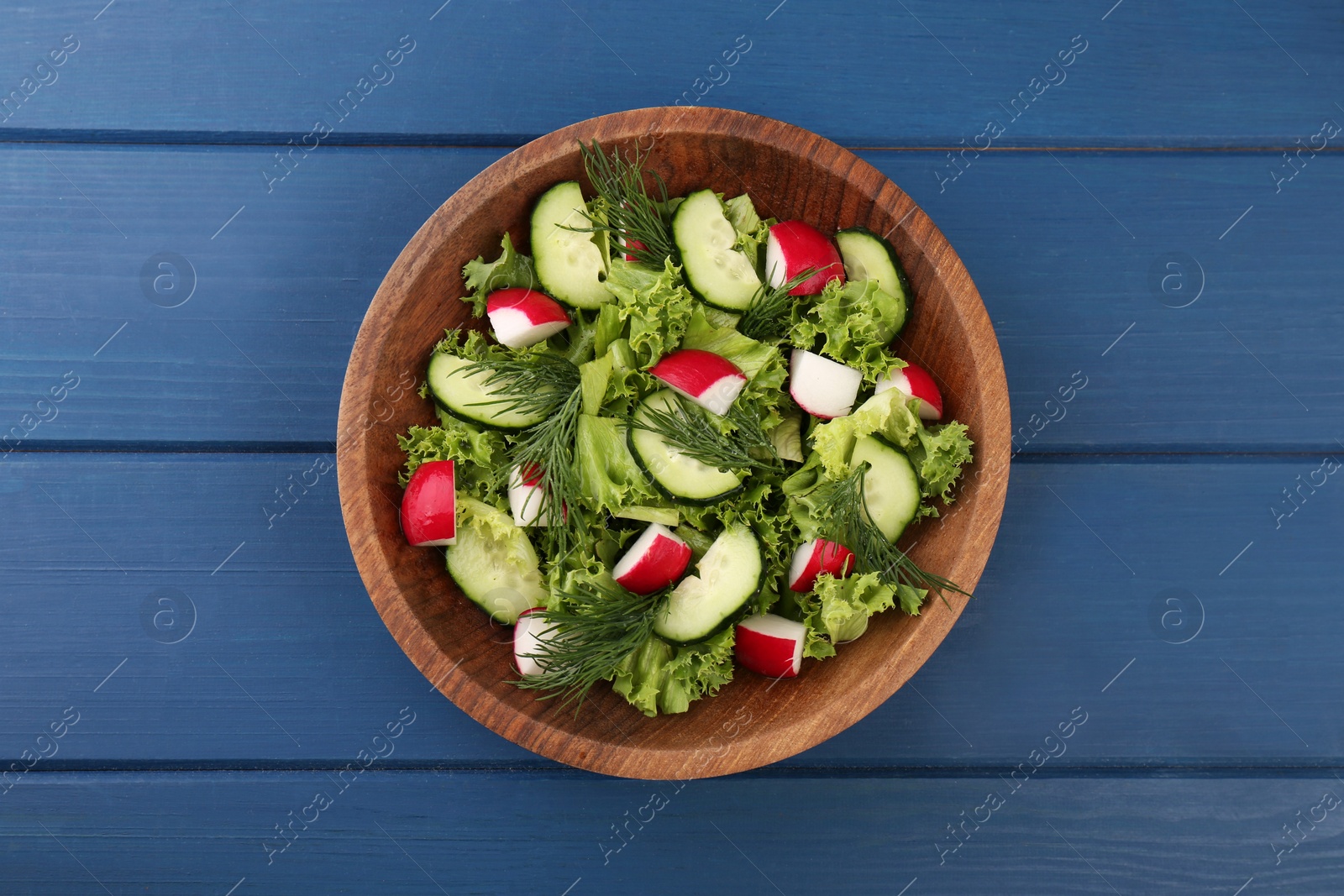 Photo of Delicious salad with radish, lettuce, dill and cucumber on blue wooden table, top view