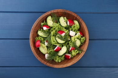 Photo of Delicious salad with radish, lettuce, dill and cucumber on blue wooden table, top view