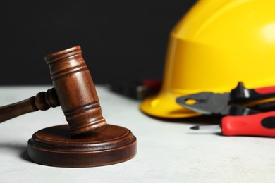 Photo of Construction and land law concepts. Gavel, hard hat and different tools on white table, closeup with space for text