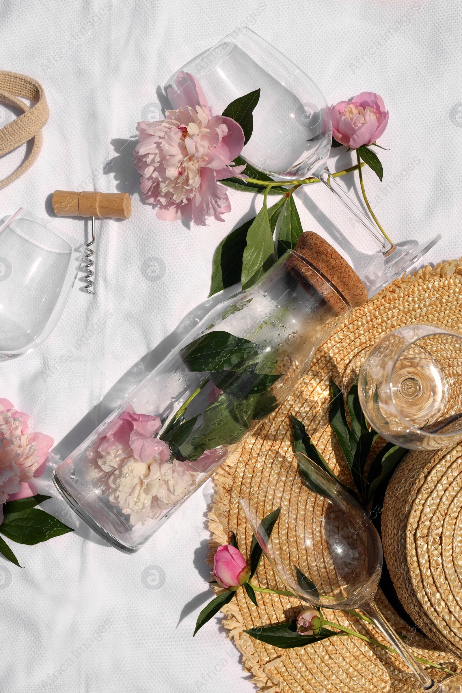 Photo of Flat lay composition with beautiful peonies and wineglasses on white fabric