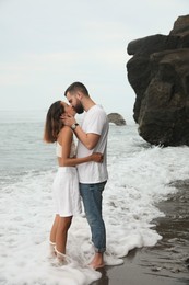 Photo of Young couple kissing on beach near sea