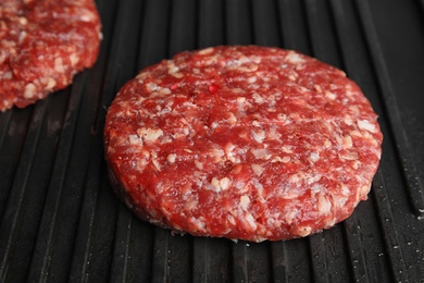 Photo of Raw meat cutlets for burger on grill, closeup