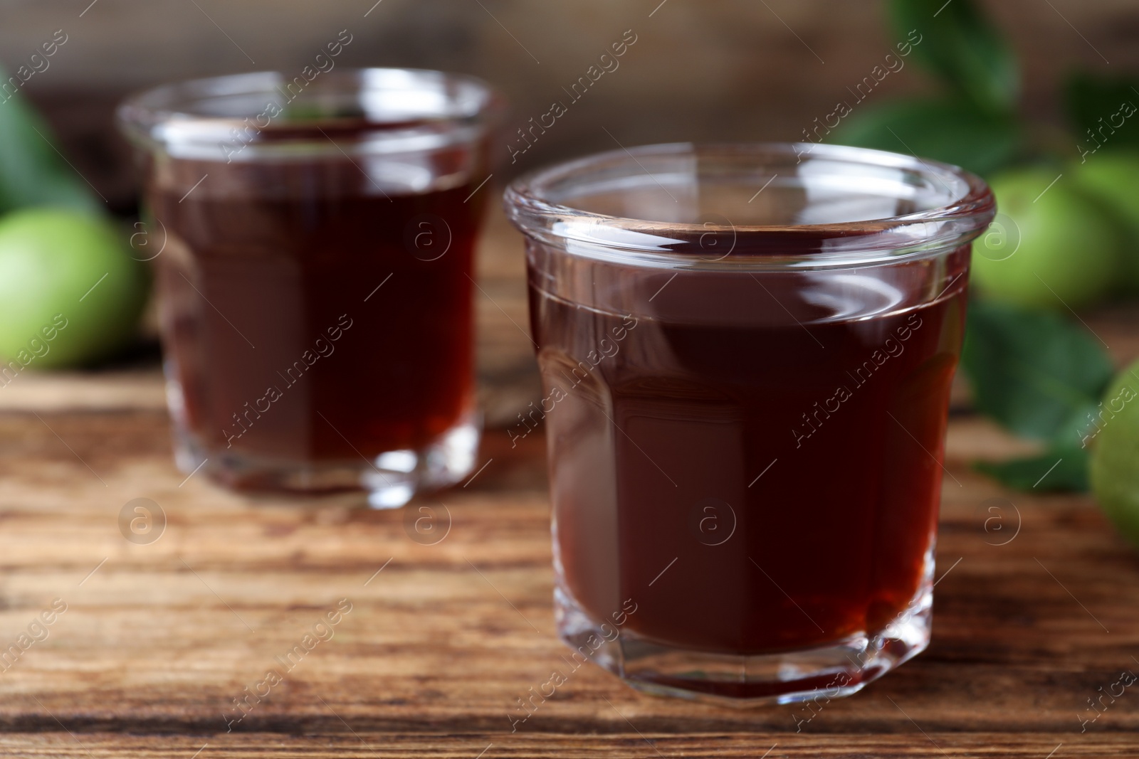 Photo of Delicious liqueur and green walnuts on wooden table. Space for text