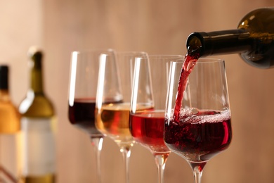 Photo of Pouring wine from bottle into glass on blurred background, closeup
