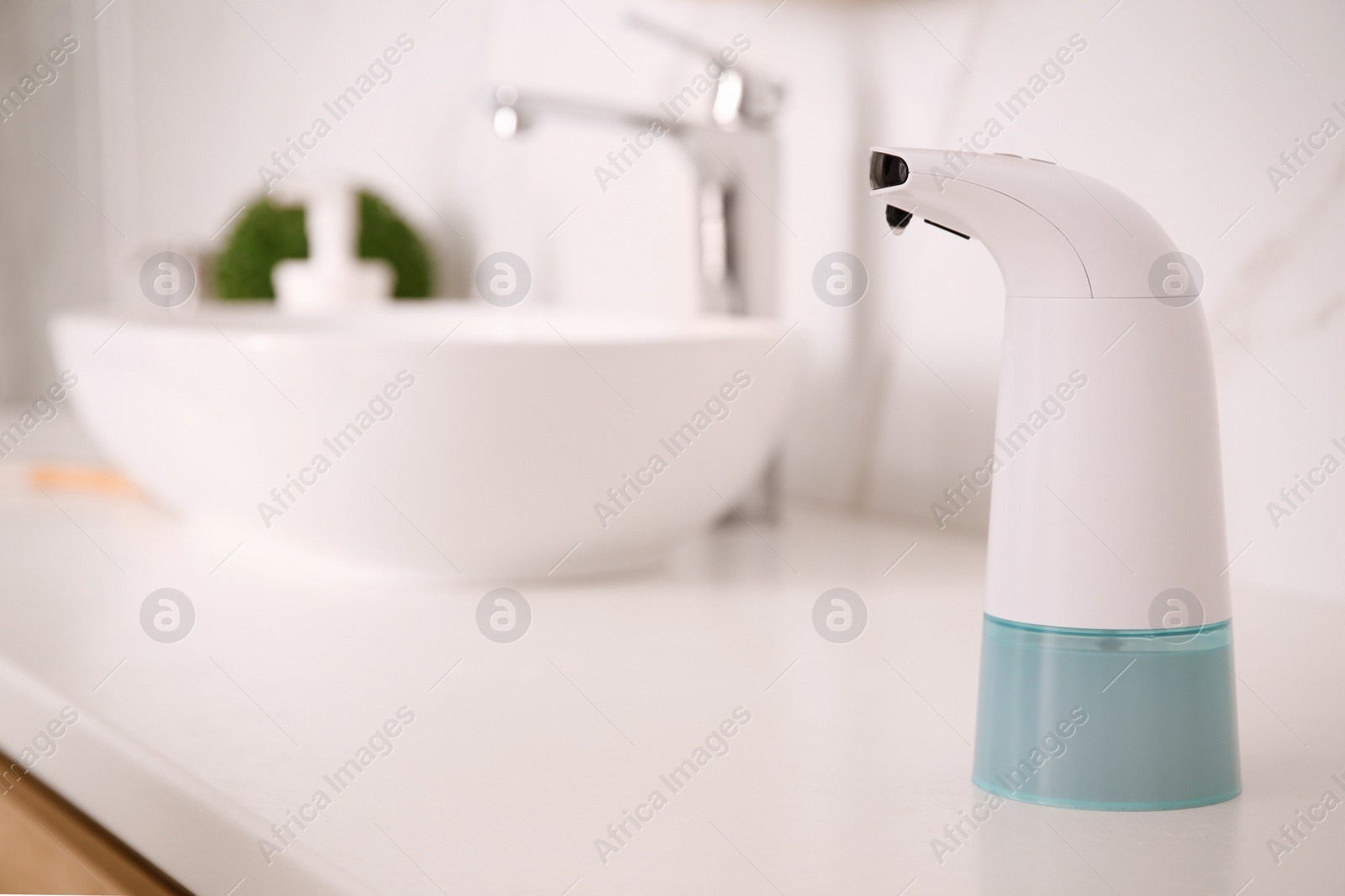 Photo of Modern automatic soap dispenser on countertop in bathroom. Space for text