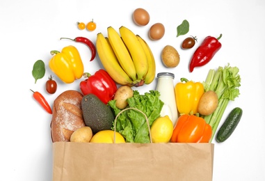 Photo of Shopping paper bag with different groceries on white background, top view