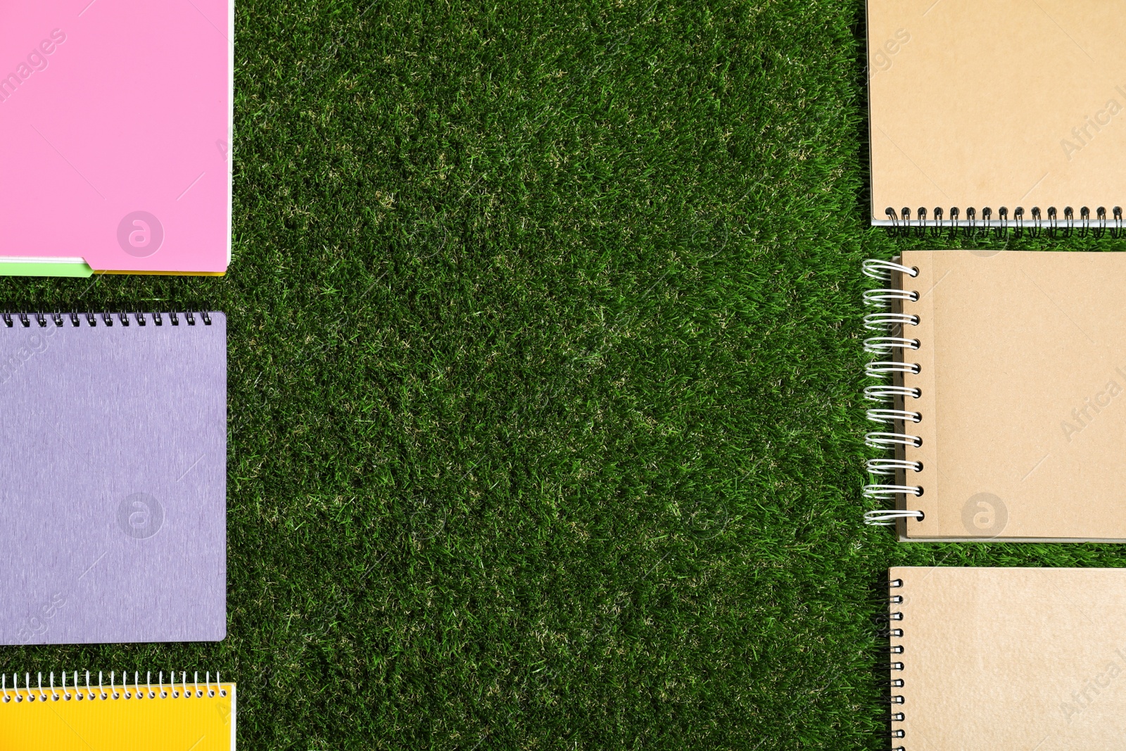 Photo of Flat lay composition with plastic and paper notebooks on green grass, space for text. Recycling concept