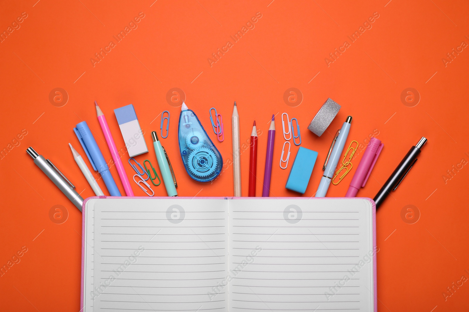 Photo of Flat lay composition with open notebook and other school stationery on red background, space for text. Back to school