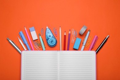 Flat lay composition with open notebook and other school stationery on red background, space for text. Back to school