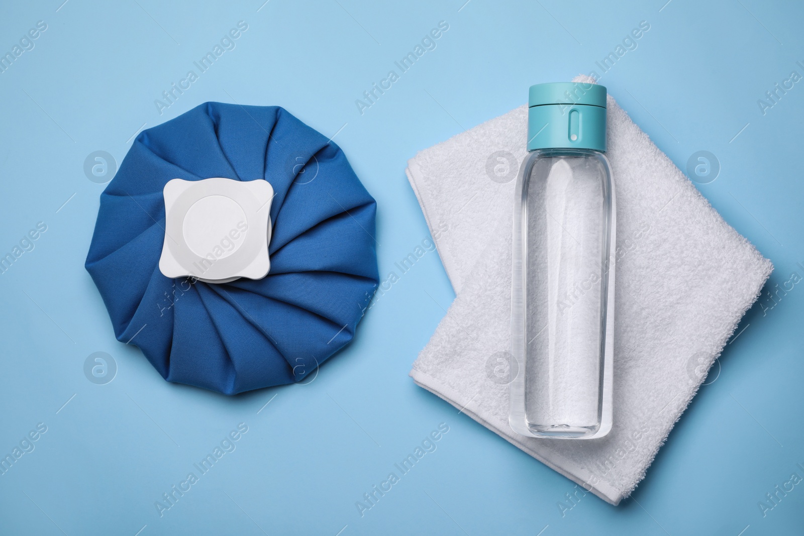 Photo of Bottle of water, cold compress and towel on light blue background, flat lay. Heat stroke treatment
