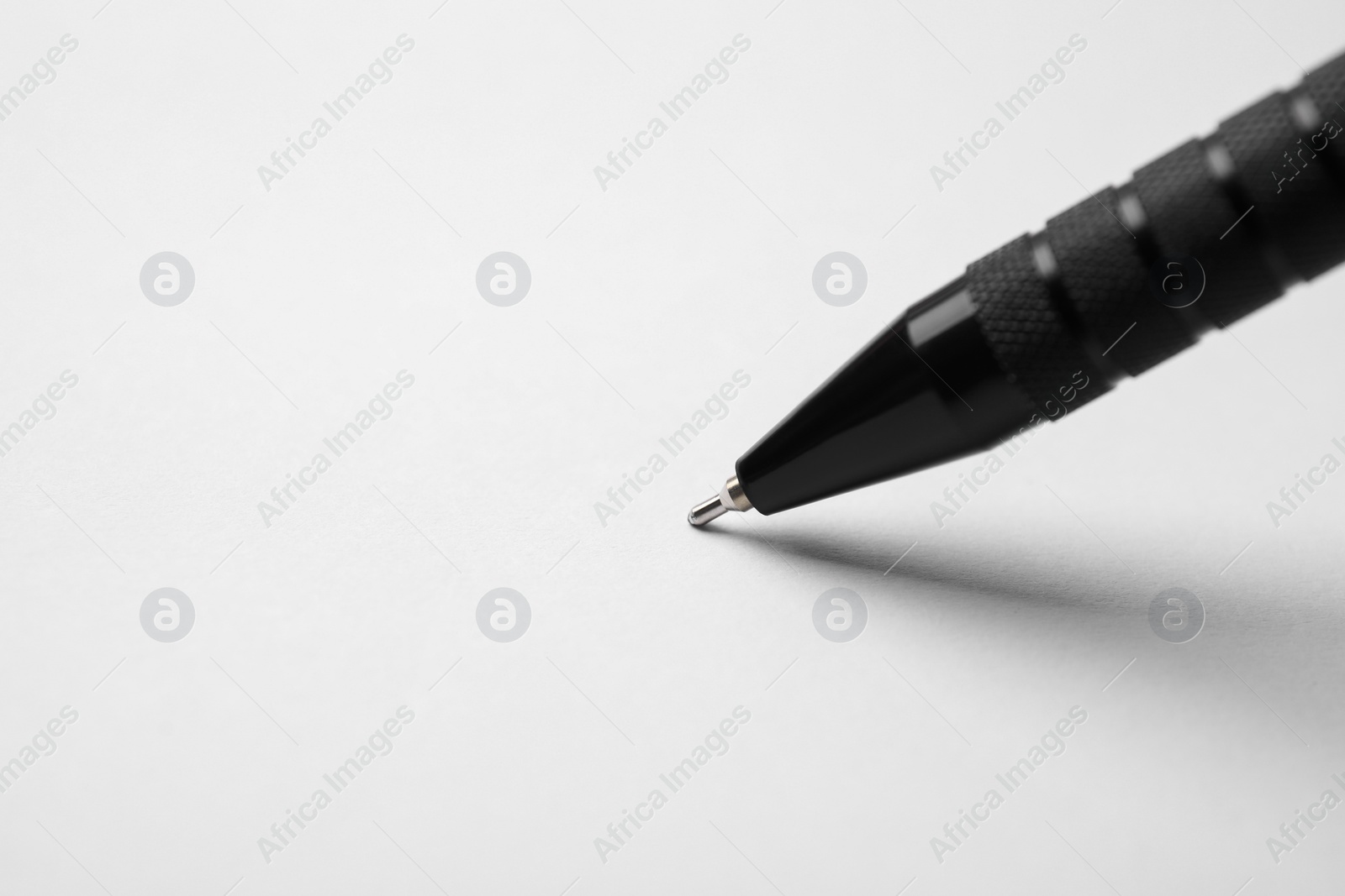 Photo of Writing on sheet of white paper with pen, closeup