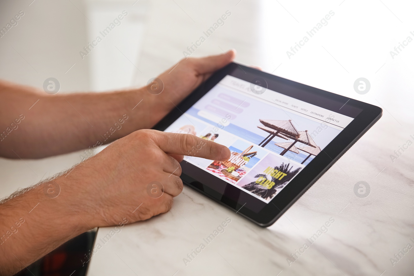Photo of Man booking tickets online on tablet at table, closeup. Travel agency concept